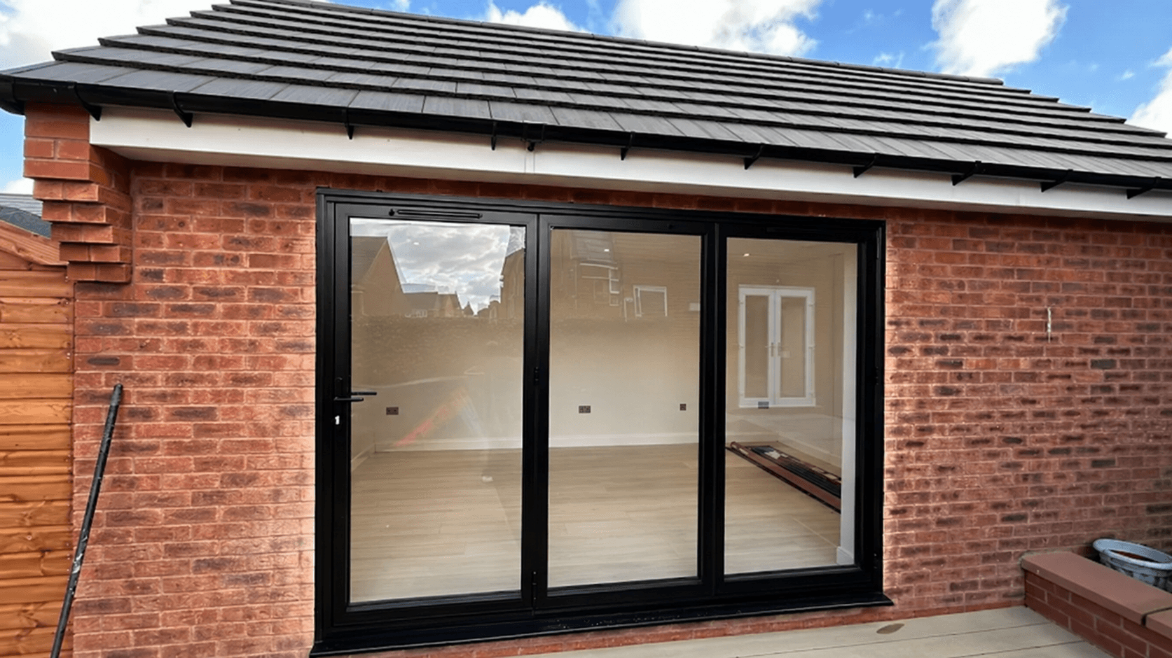 Waterfield brick extension with a pitched tiled roof and black bifold doors