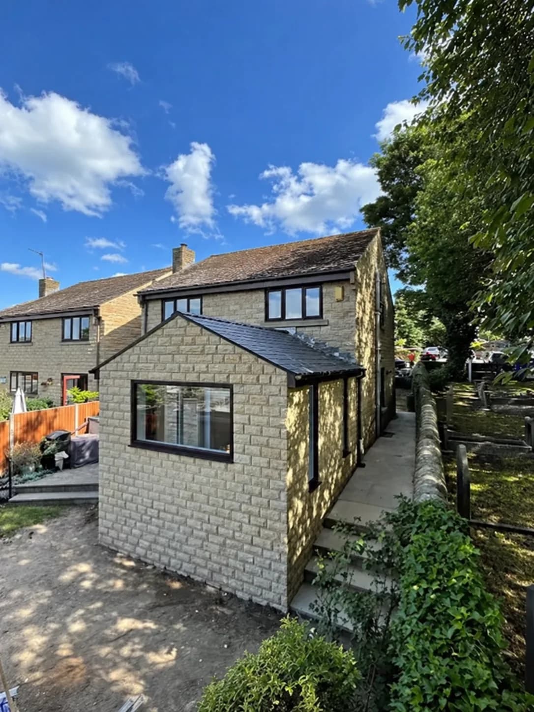 Completed stone extension with pitched tiled roof and black framed picture window